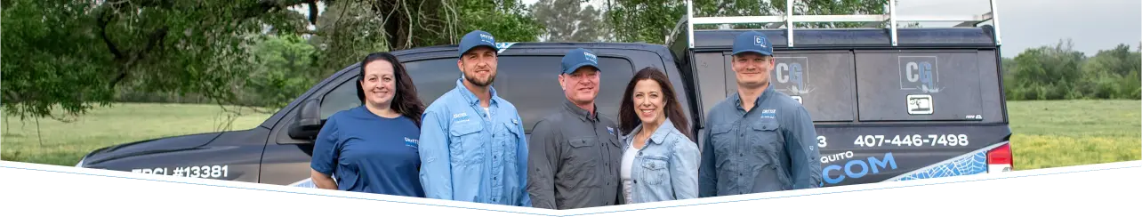Five Critter Gitters staff members posing in front of a branded service truck in a field.