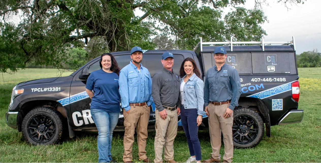 Five Critter Gitters staff members posing in front of a branded service truck in a field.