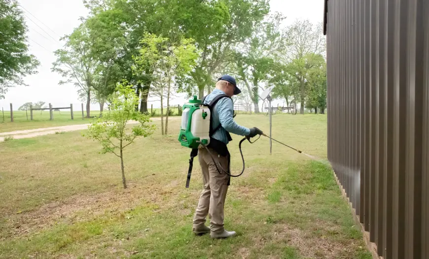Pest control technician applying treatment to building exterior in East Texas, emphasizing mosquito prevention for homeowners.