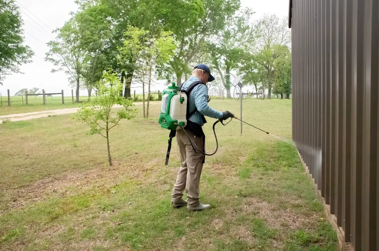 Pest control professional applying termite barrier treatment to a waterfront home